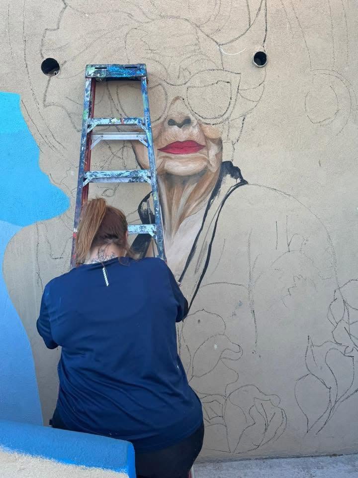 Picazo pintando el contorno de un retrato en un muro